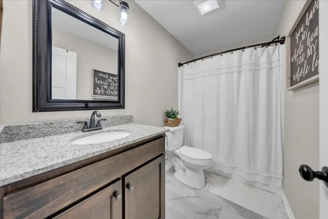 a bathroom with a granite countertop sink a toilet and a mirror
