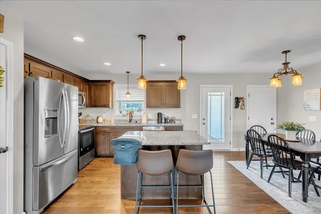 a kitchen with stainless steel appliances granite countertop a dining table chairs stove refrigerator and cabinets