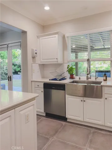 a kitchen with stainless steel appliances white cabinets a sink and a large window