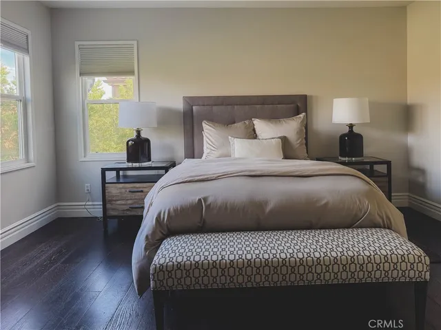 a bedroom with a bed two lamps and wooden floor