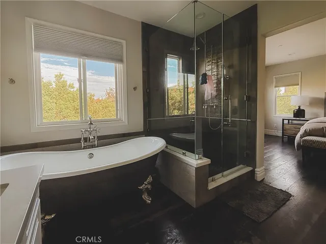 a bathroom with a tub a sink a mirror and a shower