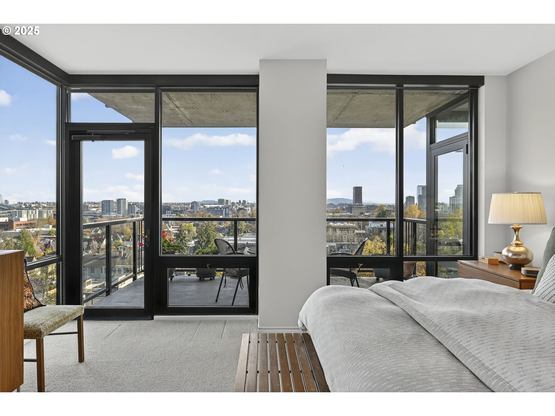2448 Northwest Westover Road, Unit E402 Portland, OR 97210 - Photo 13 of 31 a bedroom with a large bed and a lamp next to a large window