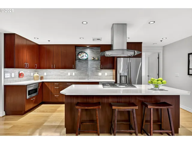a kitchen with kitchen island granite countertop a sink cabinets and stainless steel appliances