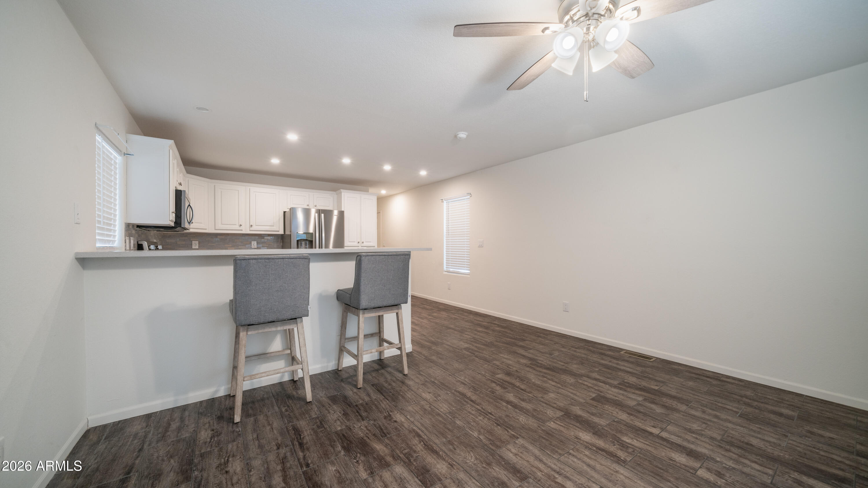2929 East Main Street, Unit 237 Mesa, AZ 85213 - Photo 4 of 20 a kitchen with kitchen island stainless steel appliances a dining table chairs and white cabinets