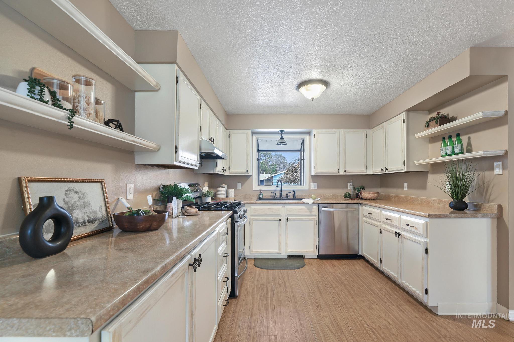 1143 Starfire Street Twin Falls, ID 83301 - Photo 11 of 32 Kitchen featuring open shelves, stainless steel appliances, light countertops, a textured ceiling, and white cabinets