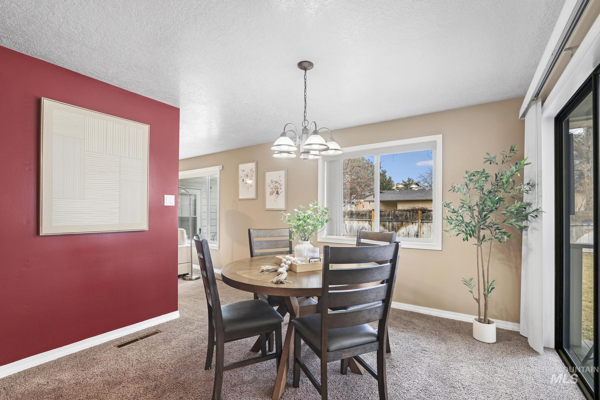 1143 Starfire Street Twin Falls, ID 83301 - Photo 12 of 32 Dining room featuring a textured ceiling, light colored carpet, and a chandelier