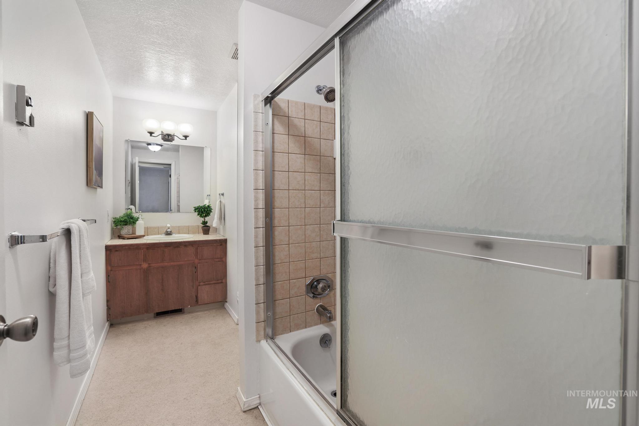 1143 Starfire Street Twin Falls, ID 83301 - Photo 22 of 32 Full bathroom with shower / bath combination with glass door, a textured ceiling, and vanity