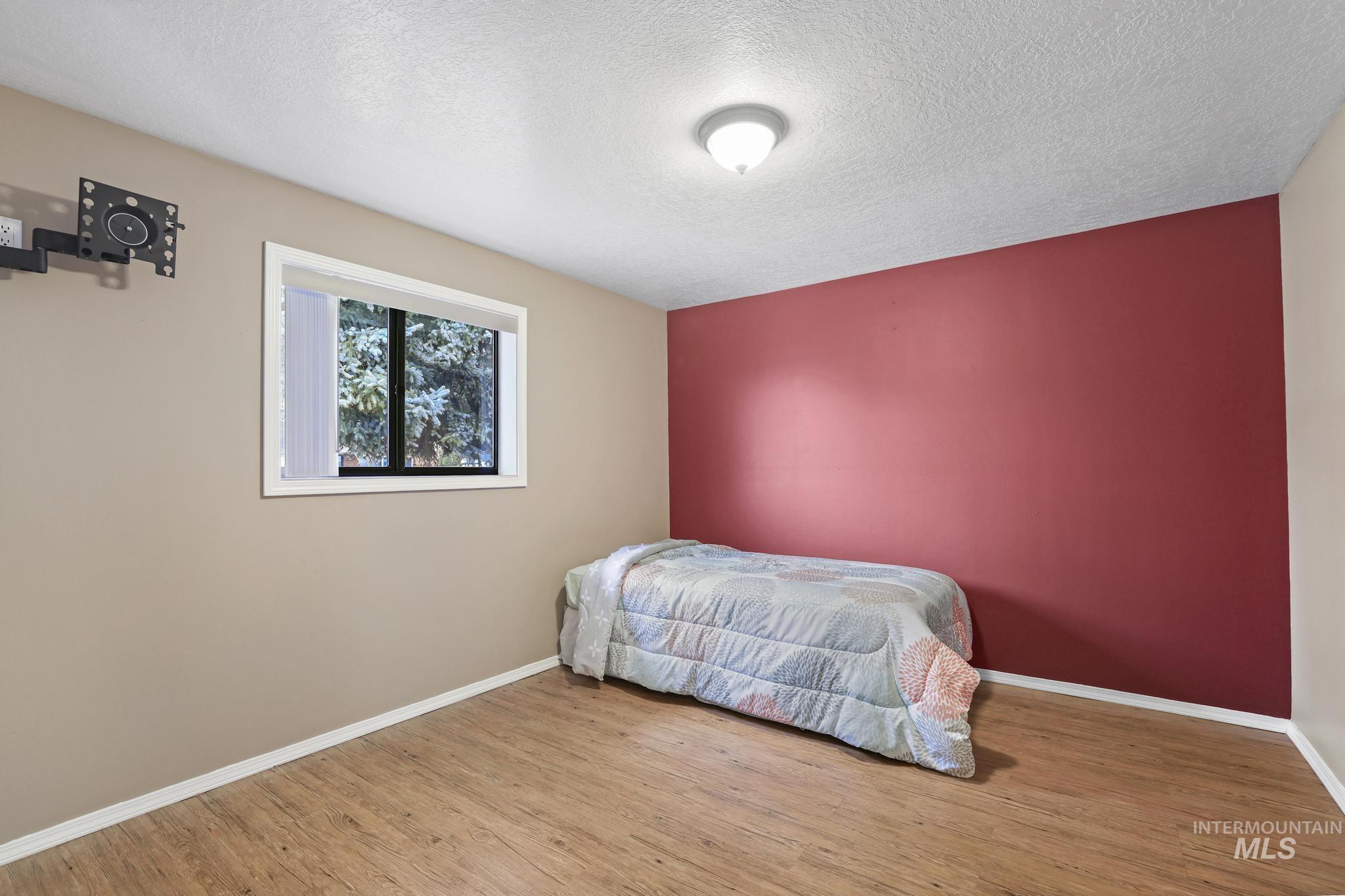 1143 Starfire Street Twin Falls, ID 83301 - Photo 24 of 32 Bedroom with wood finished floors, a textured ceiling, and an accent wall
