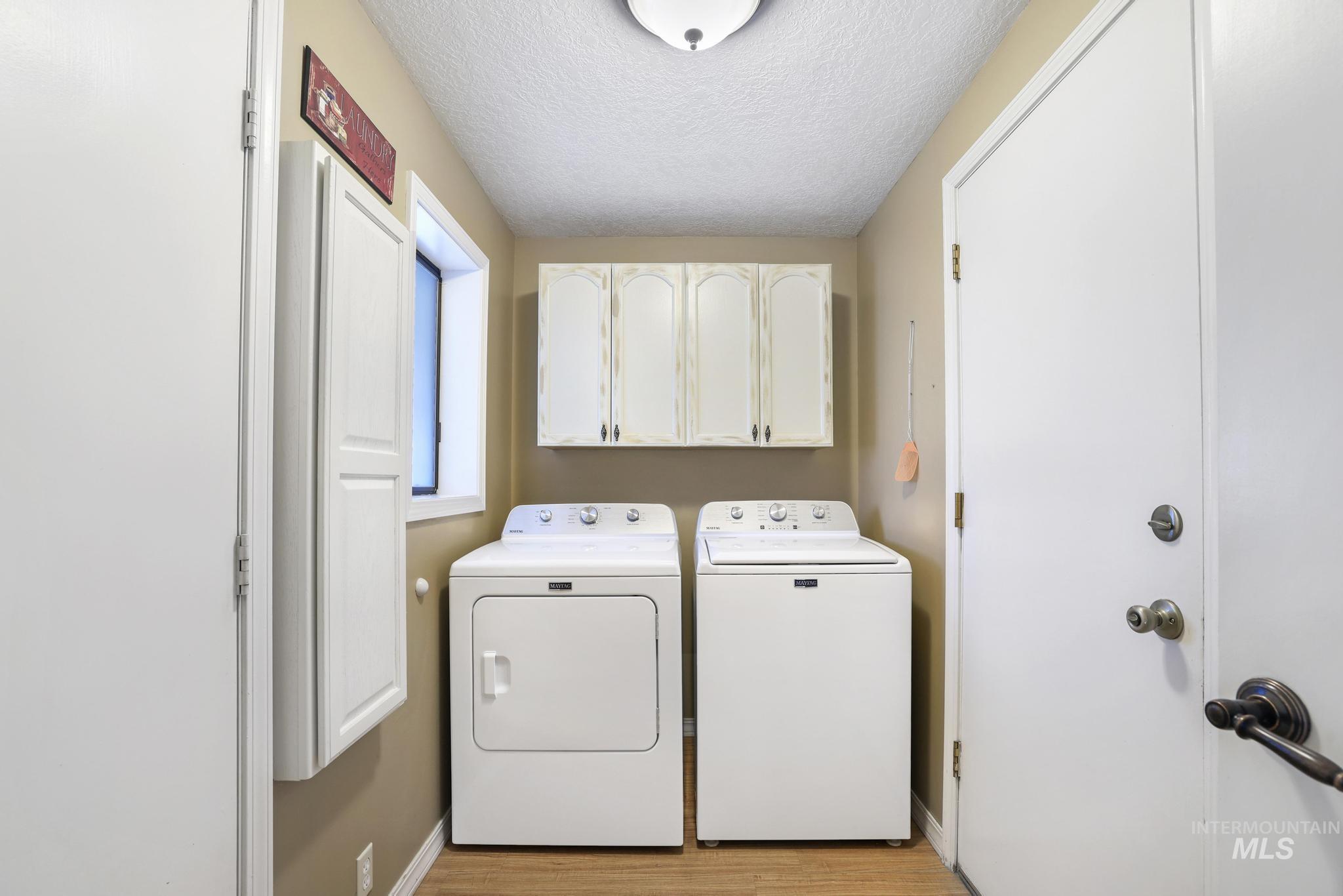 1143 Starfire Street Twin Falls, ID 83301 - Photo 26 of 32 Laundry room featuring a textured ceiling, cabinet space, washing machine and clothes dryer, and light wood-type flooring