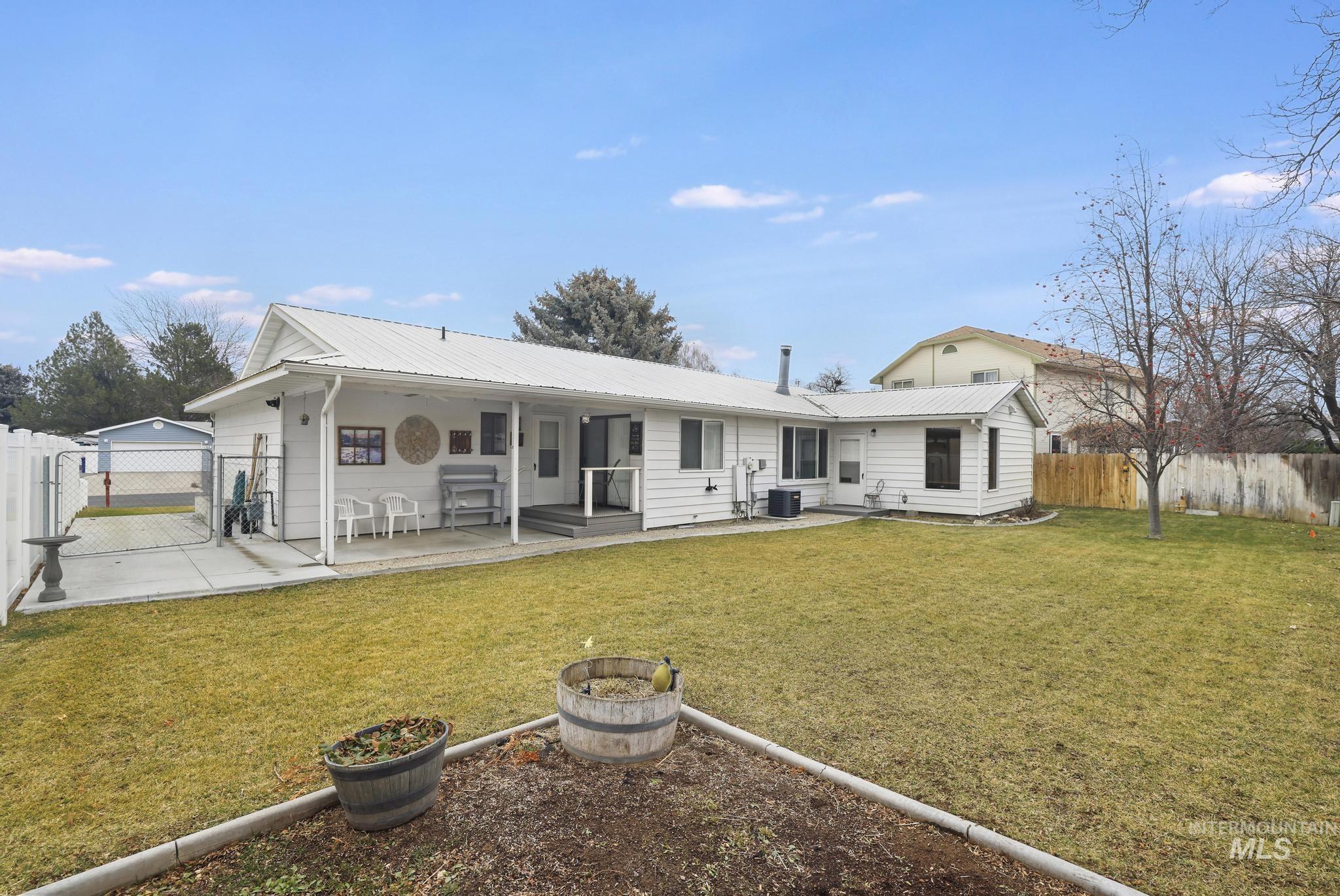 1143 Starfire Street Twin Falls, ID 83301 - Photo 28 of 32 Back of house featuring a fenced backyard, a patio area, an outdoor fire pit, a metal roof, and a gate