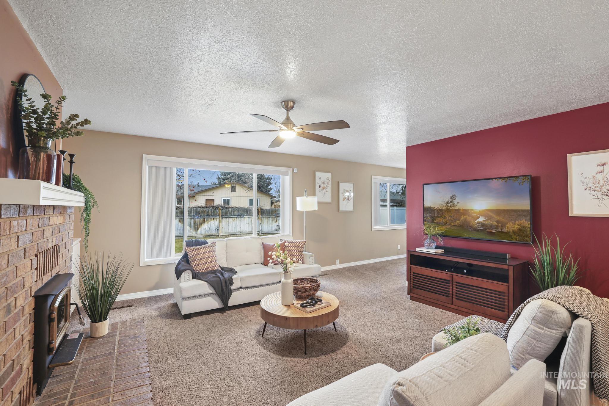 1143 Starfire Street Twin Falls, ID 83301 - Photo 6 of 32 Carpeted living area with a textured ceiling, ceiling fan, and a brick fireplace