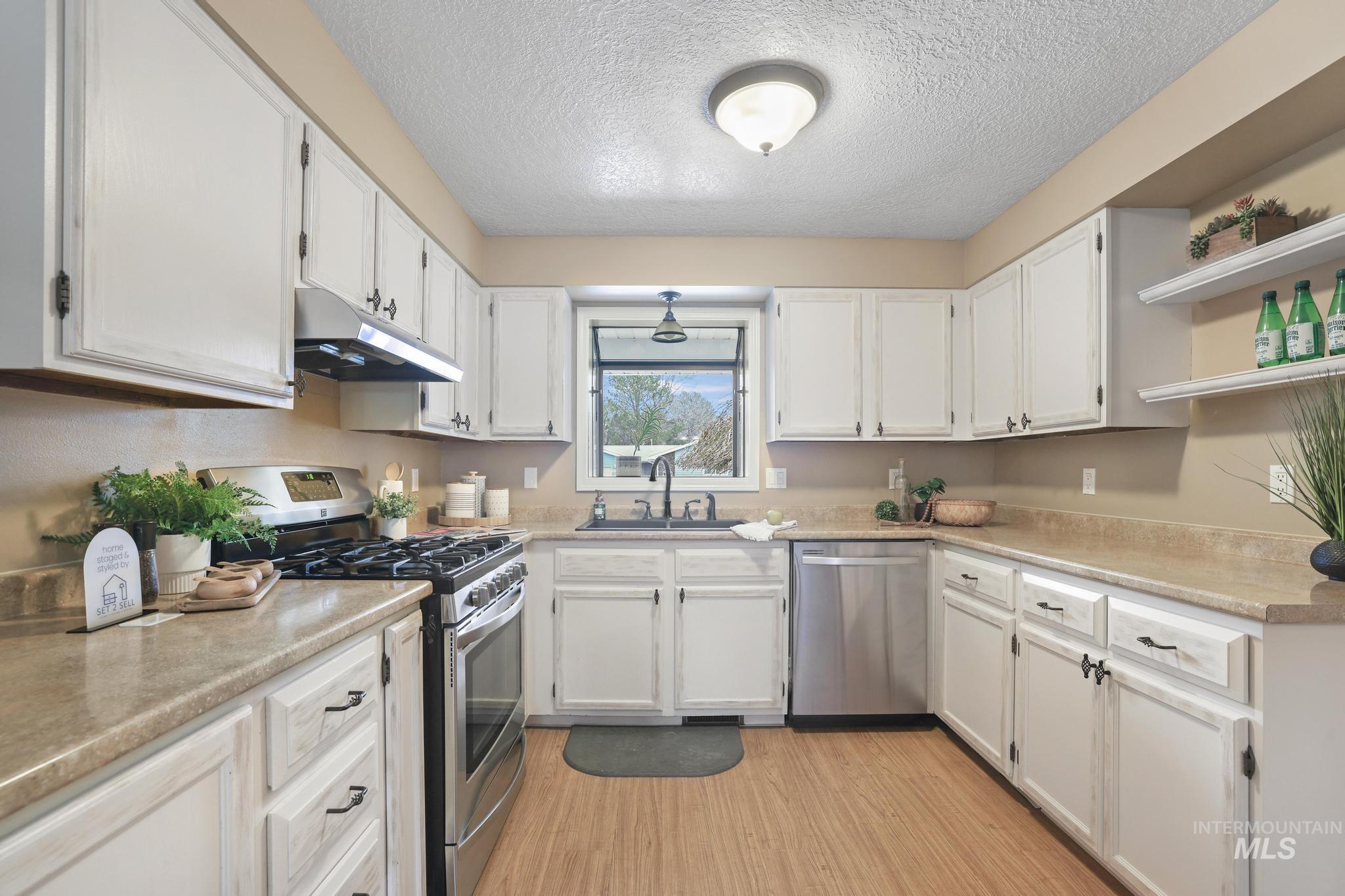 1143 Starfire Street Twin Falls, ID 83301 - Photo 7 of 32 Kitchen featuring stainless steel appliances, open shelves, white cabinetry, a textured ceiling, and under cabinet range hood