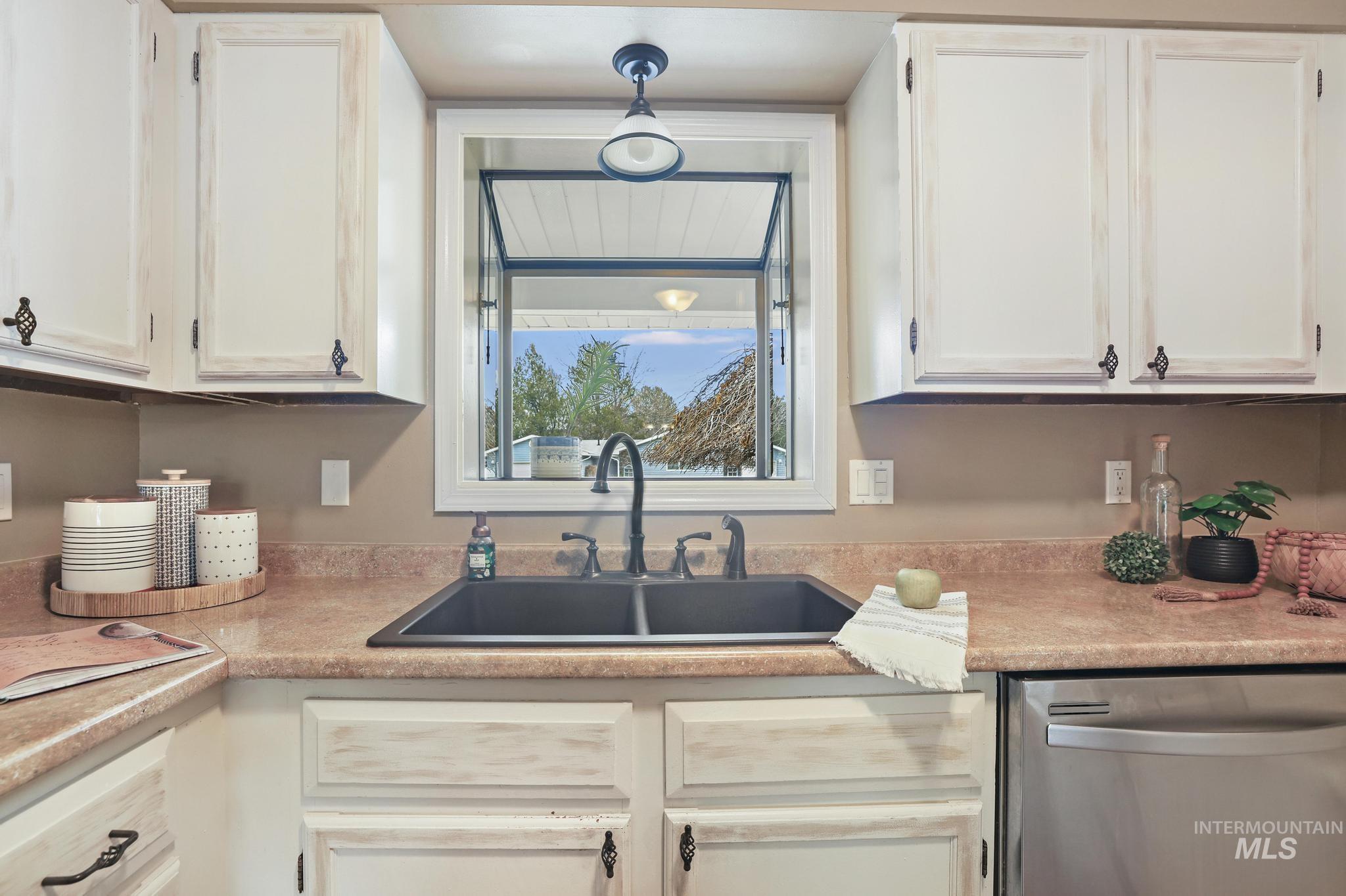 1143 Starfire Street Twin Falls, ID 83301 - Photo 10 of 32 Kitchen with dishwasher, light countertops, and white cabinetry