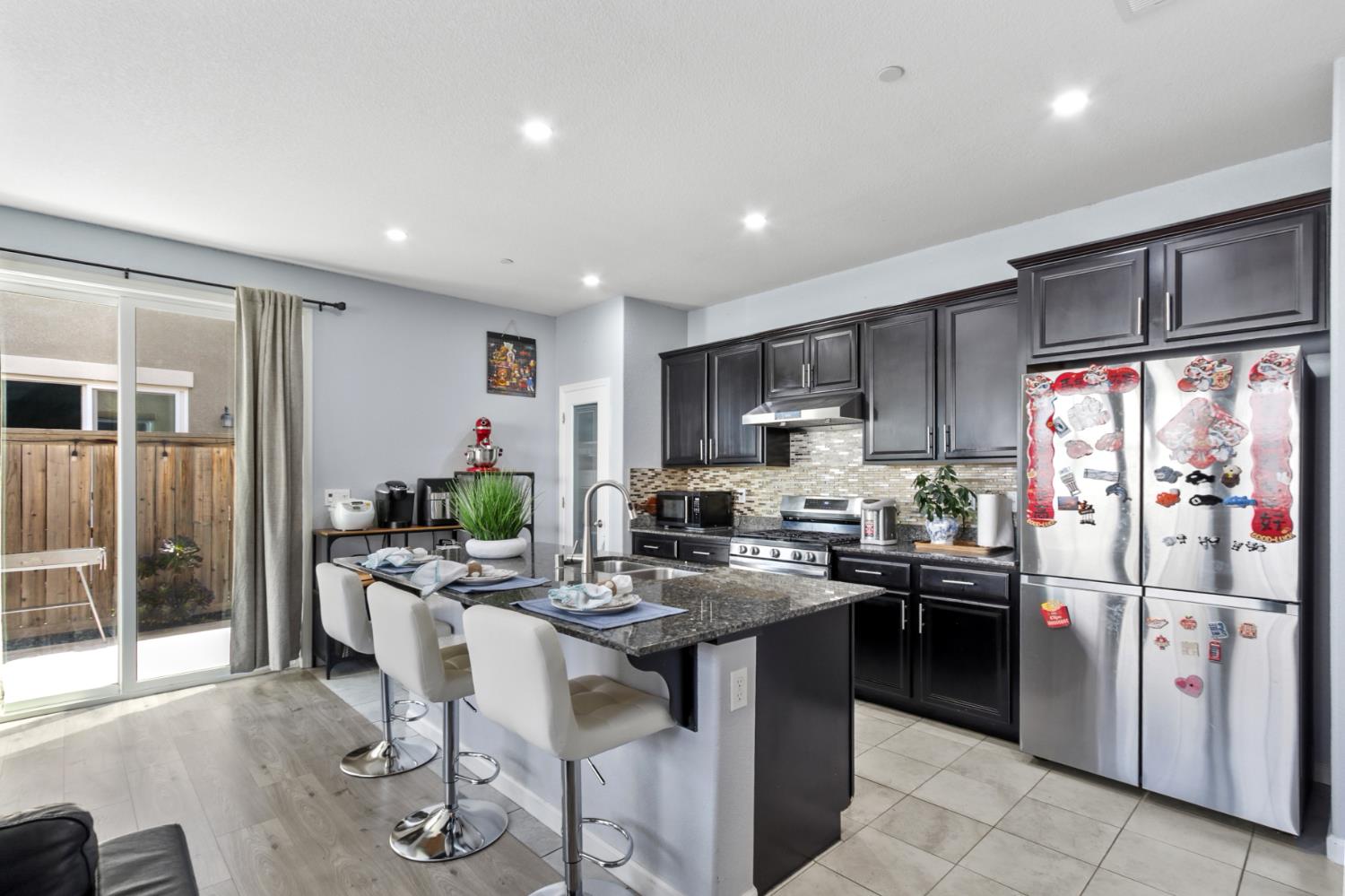 8196 Kramer Ranch Way Elk Grove, CA 95758 - Photo 14 of 47 a kitchen with stainless steel appliances kitchen island granite countertop a refrigerator a sink a stove and white cabinets