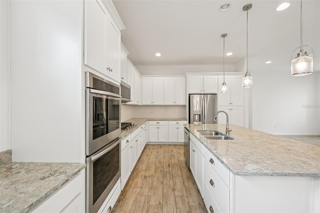 806 Winterside Drive Apollo Beach, FL 33572 - Photo 7 of 57 a large kitchen with kitchen island a large counter top a sink appliances and cabinets