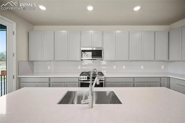 a kitchen with granite countertop a sink a stove and a microwave with cabinets