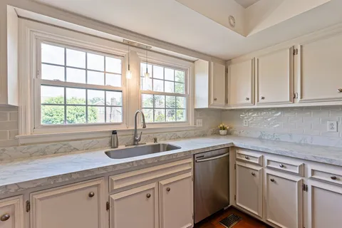 a kitchen with stainless steel appliances granite countertop white cabinets and a refrigerator