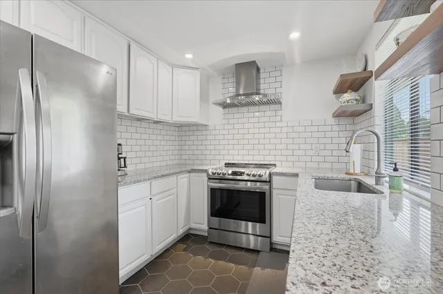 a kitchen with stainless steel appliances granite countertop a sink a stove and a refrigerator