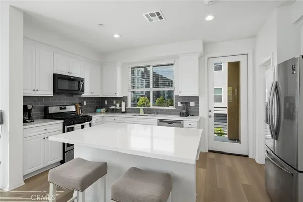 a kitchen with a refrigerator a stove a sink a dining table and chairs