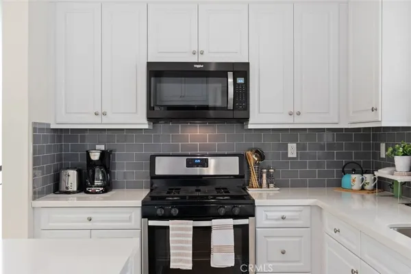 a kitchen with white cabinets and appliances