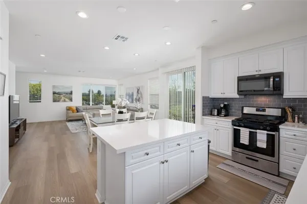 a large white kitchen with stainless steel appliances granite countertop a lot of counter space and a sink