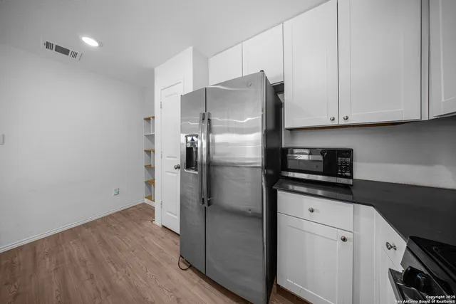 a kitchen with stainless steel appliances granite countertop a refrigerator a stove and white cabinets