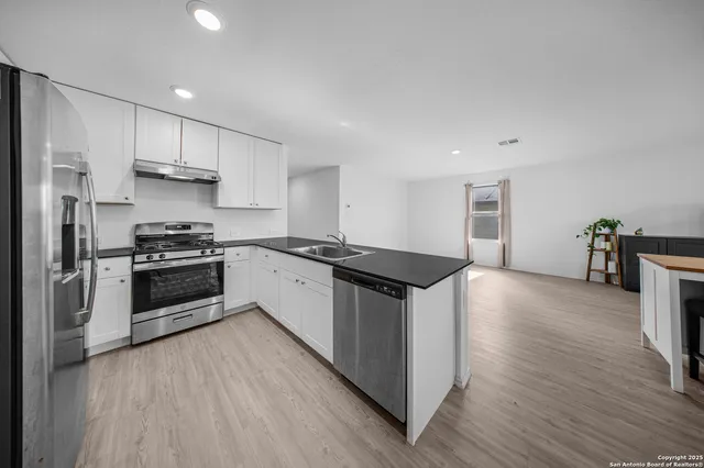 a kitchen with stainless steel appliances a stove a sink and a refrigerator