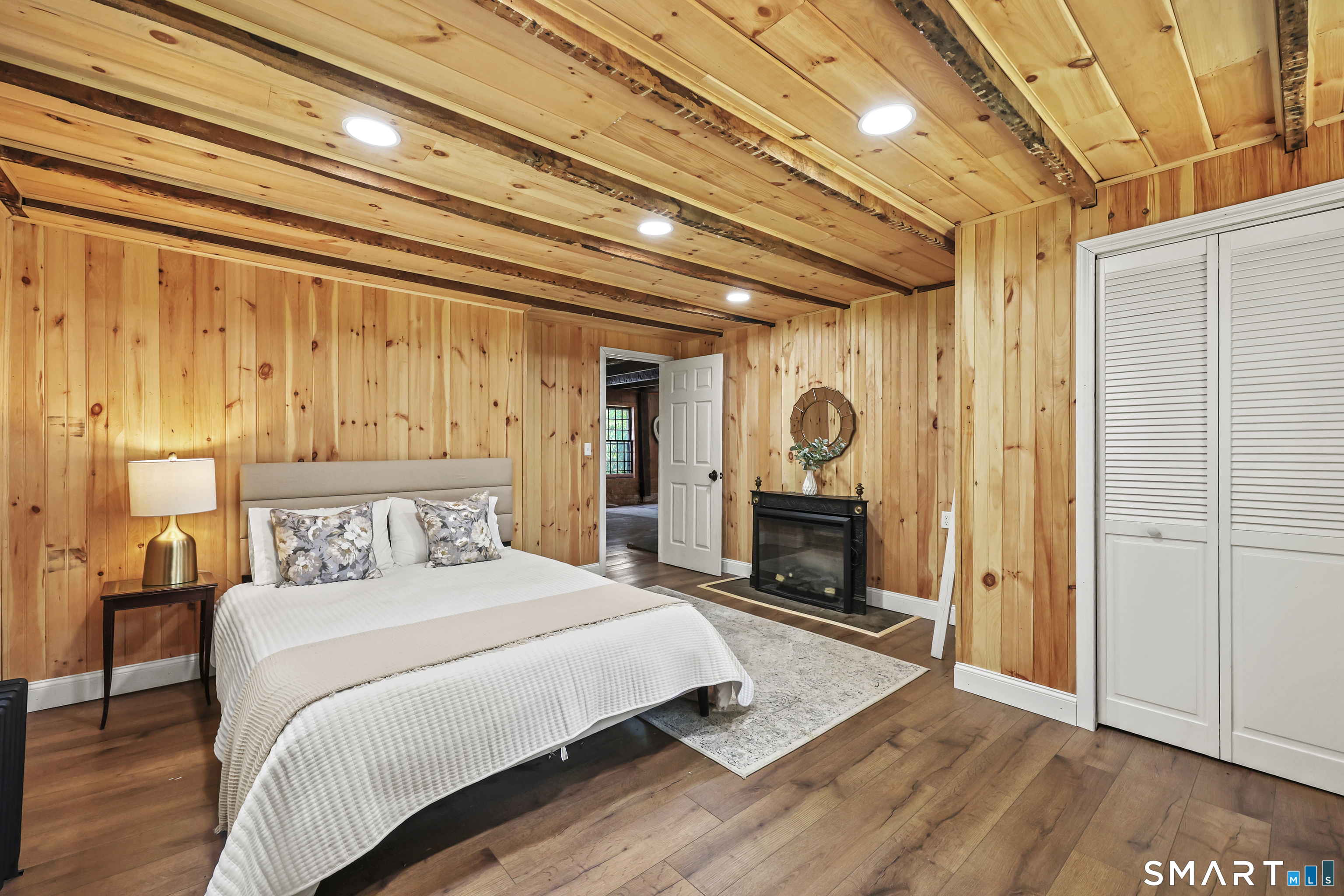 2880 Main Street Coventry, CT 06238 - Photo 18 of 40 Main level remodeled bedroom complete with LVT flooring, electric fireplace insert, beams, & paneled walls.