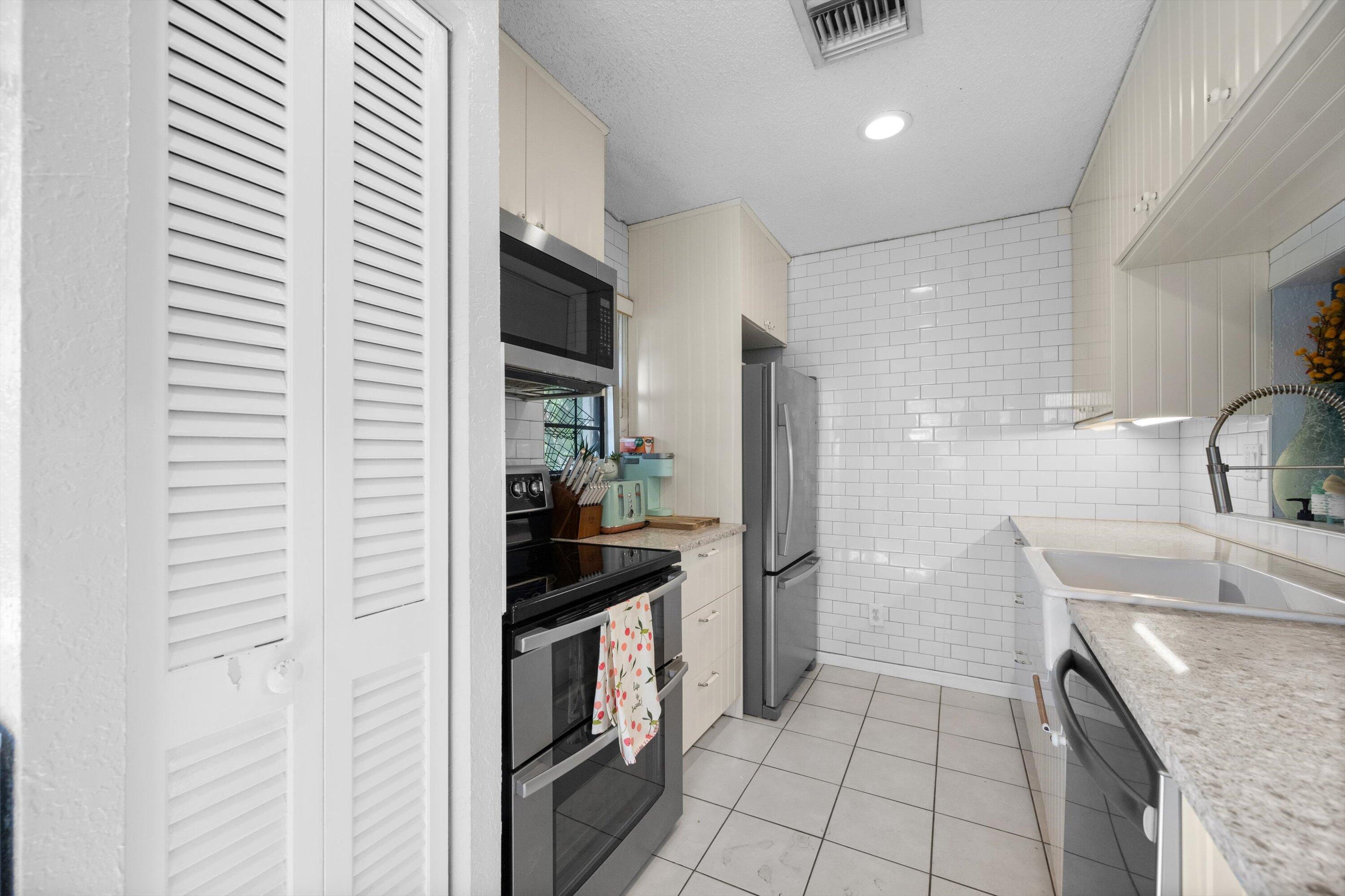 197 Southeast 1st Circle, Unit 15B Boynton Beach, FL 33435 - Photo 13 of 26 a kitchen with stainless steel appliances granite countertop a sink and a stove