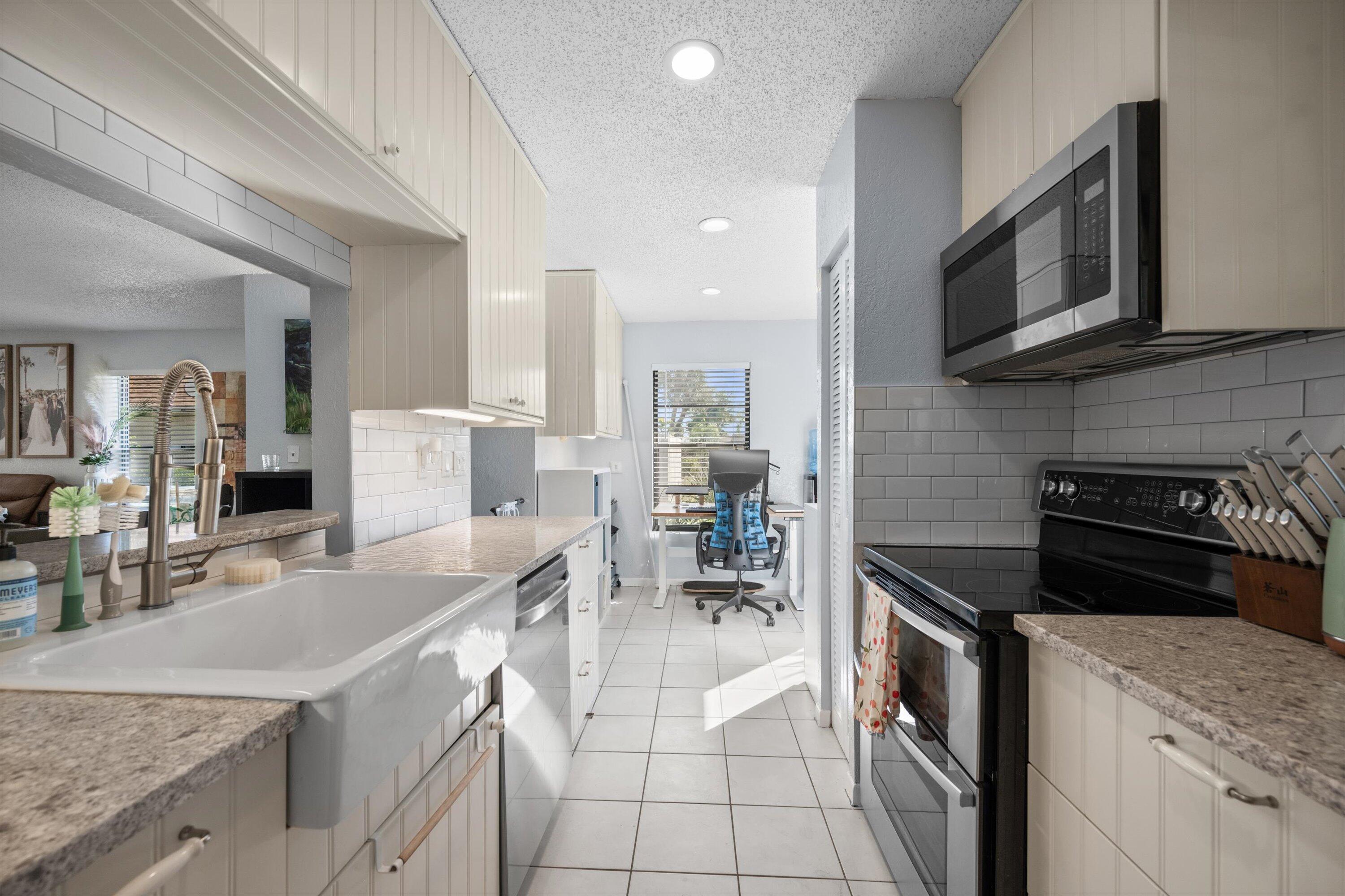 197 Southeast 1st Circle, Unit 15B Boynton Beach, FL 33435 - Photo 15 of 26 a kitchen with stainless steel appliances granite countertop a stove top oven a sink a dining table and chairs