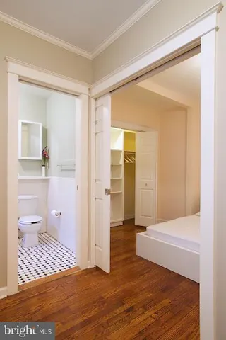 a view of a hallway with wooden floor and a bathroom