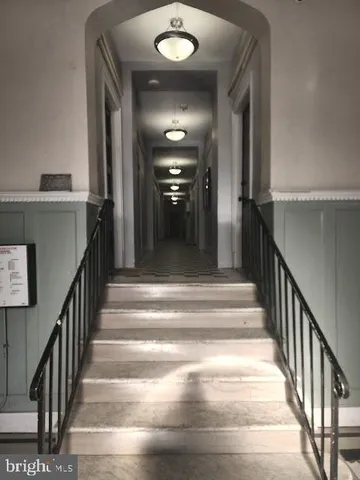 a view of staircase with railing and a chandelier