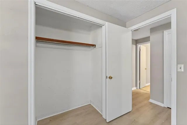 a view of an empty room with wooden floor and closet