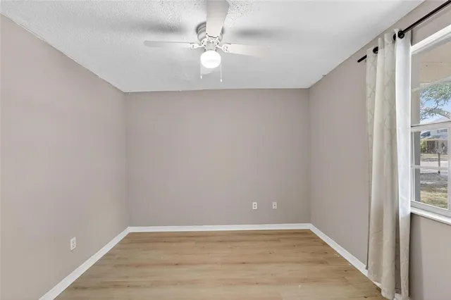 a view of an empty room with wooden floor and window