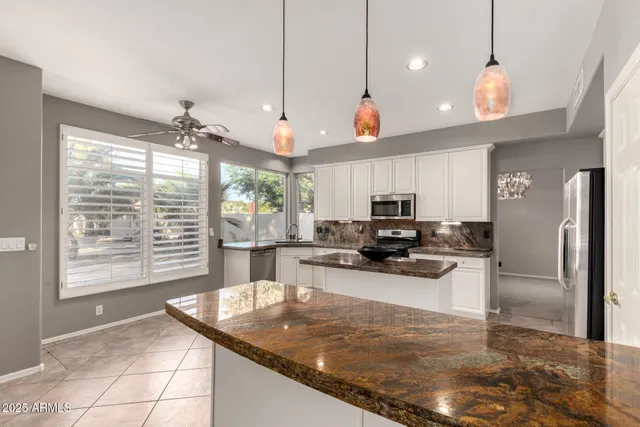 a kitchen with a stove a sink a refrigerator and chairs