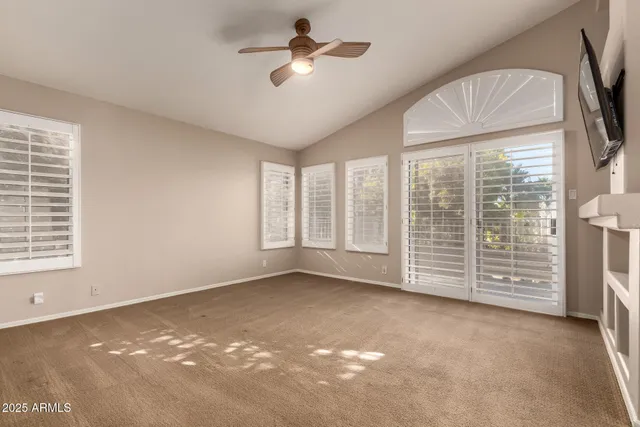 a view of an empty room with a window and a kitchen