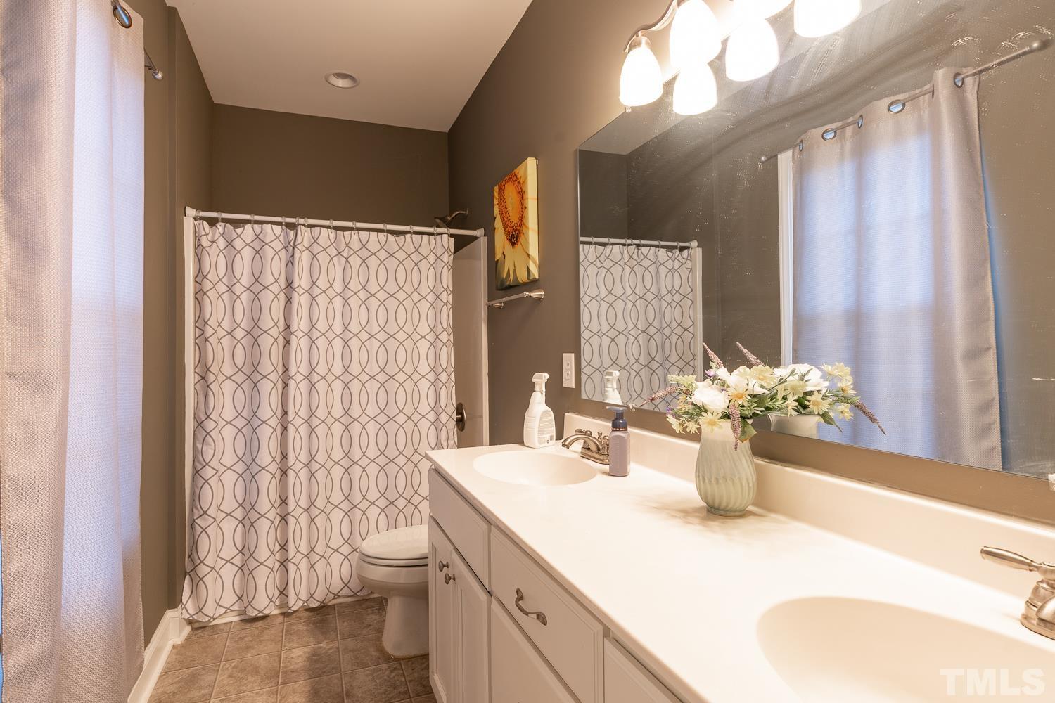 532 Cooper Street Clayton, NC 27520 - Photo 22 of 33 a bathroom with a granite countertop sink a toilet and a large mirror