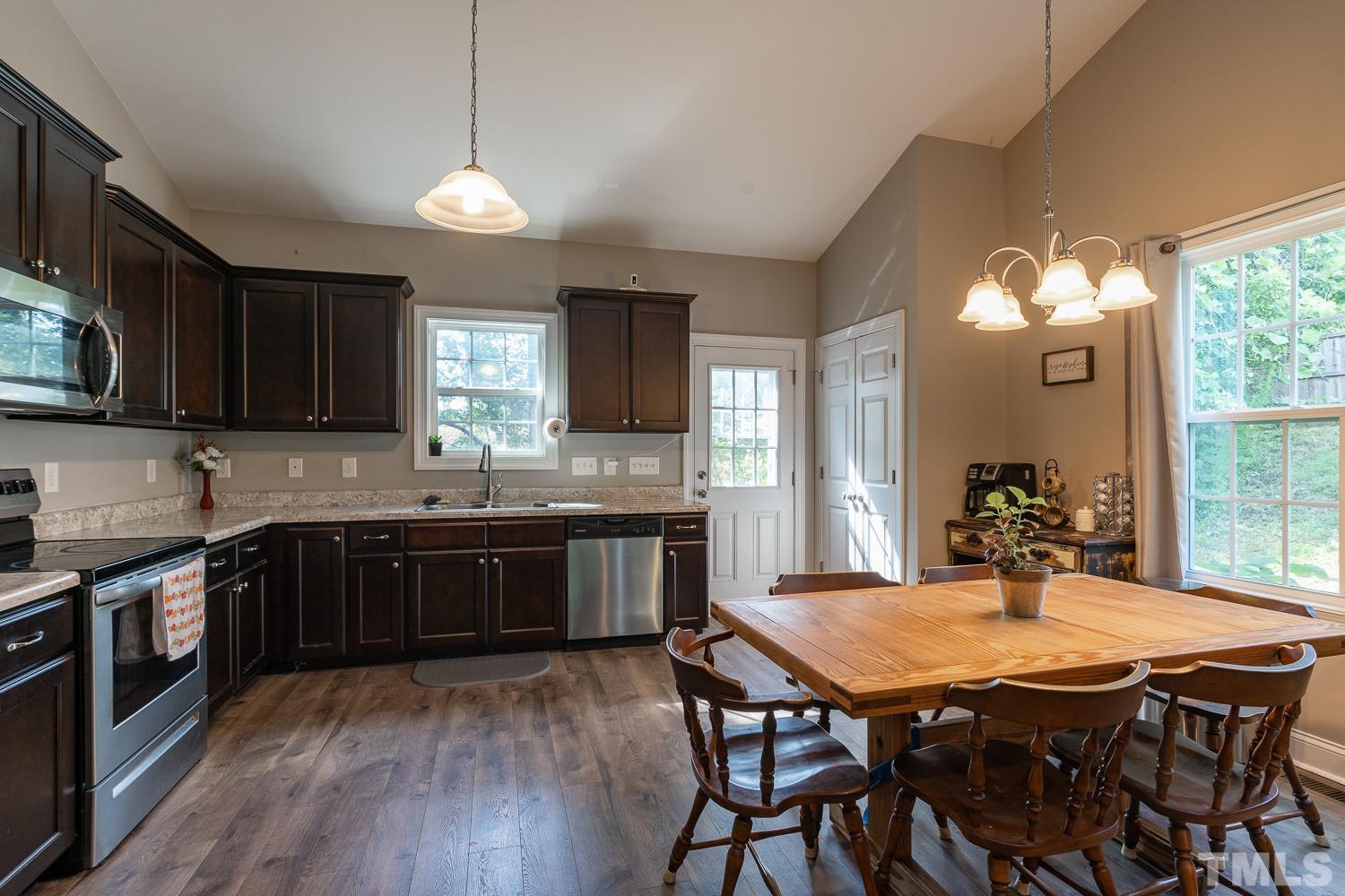 532 Cooper Street Clayton, NC 27520 - Photo 5 of 33 a kitchen with a stove a sink dishwasher a dining table and chairs with wooden floor