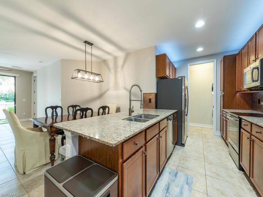 7777 Bristol Circle Naples, FL 34120 - Photo 6 of 22 a kitchen with granite countertop a stove a sink a dining table and chairs