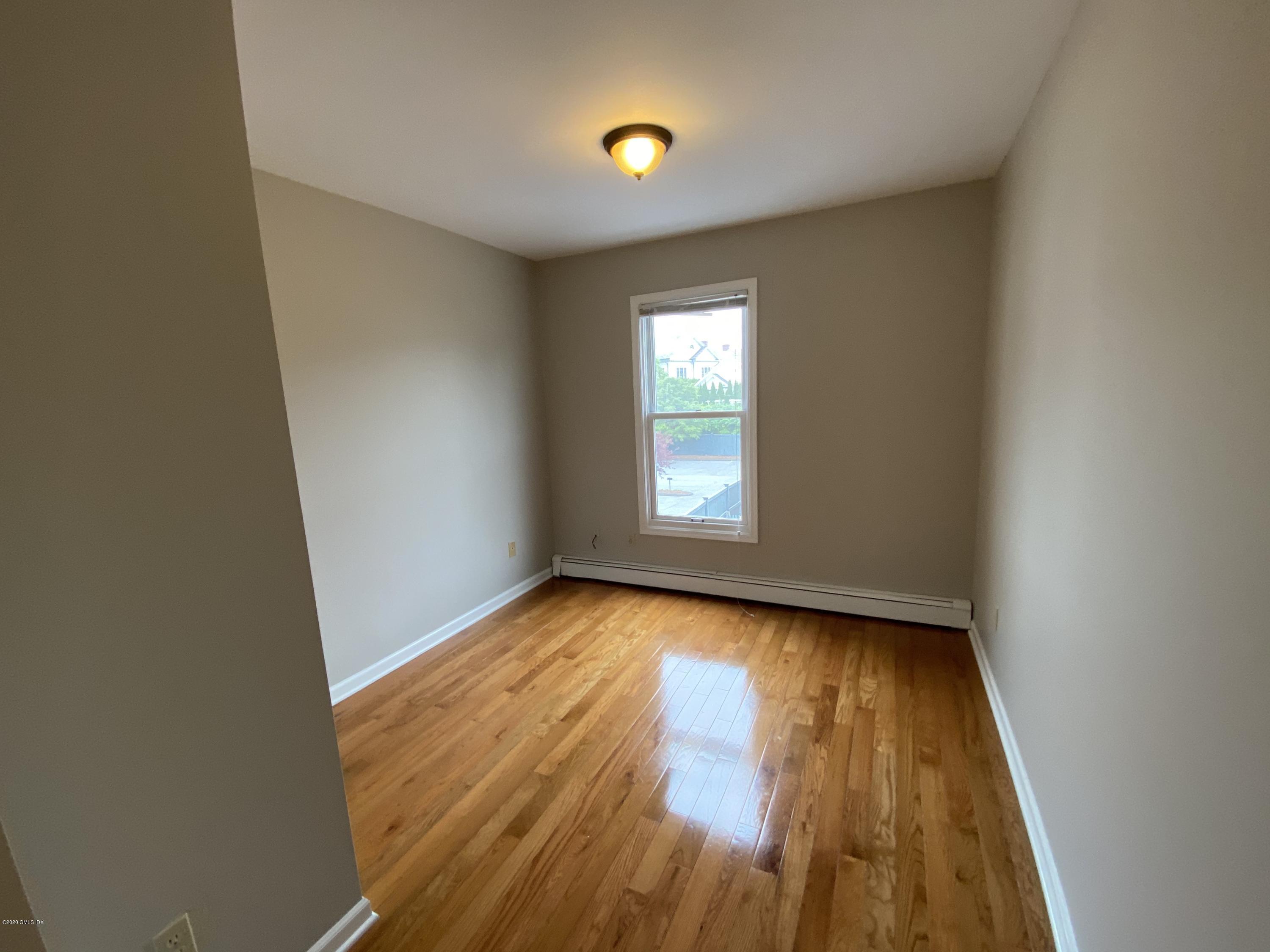 131 Mason Street, Unit 2 Greenwich, CT 06830 - Photo 12 of 14 a view of an empty room with wooden floor and a window