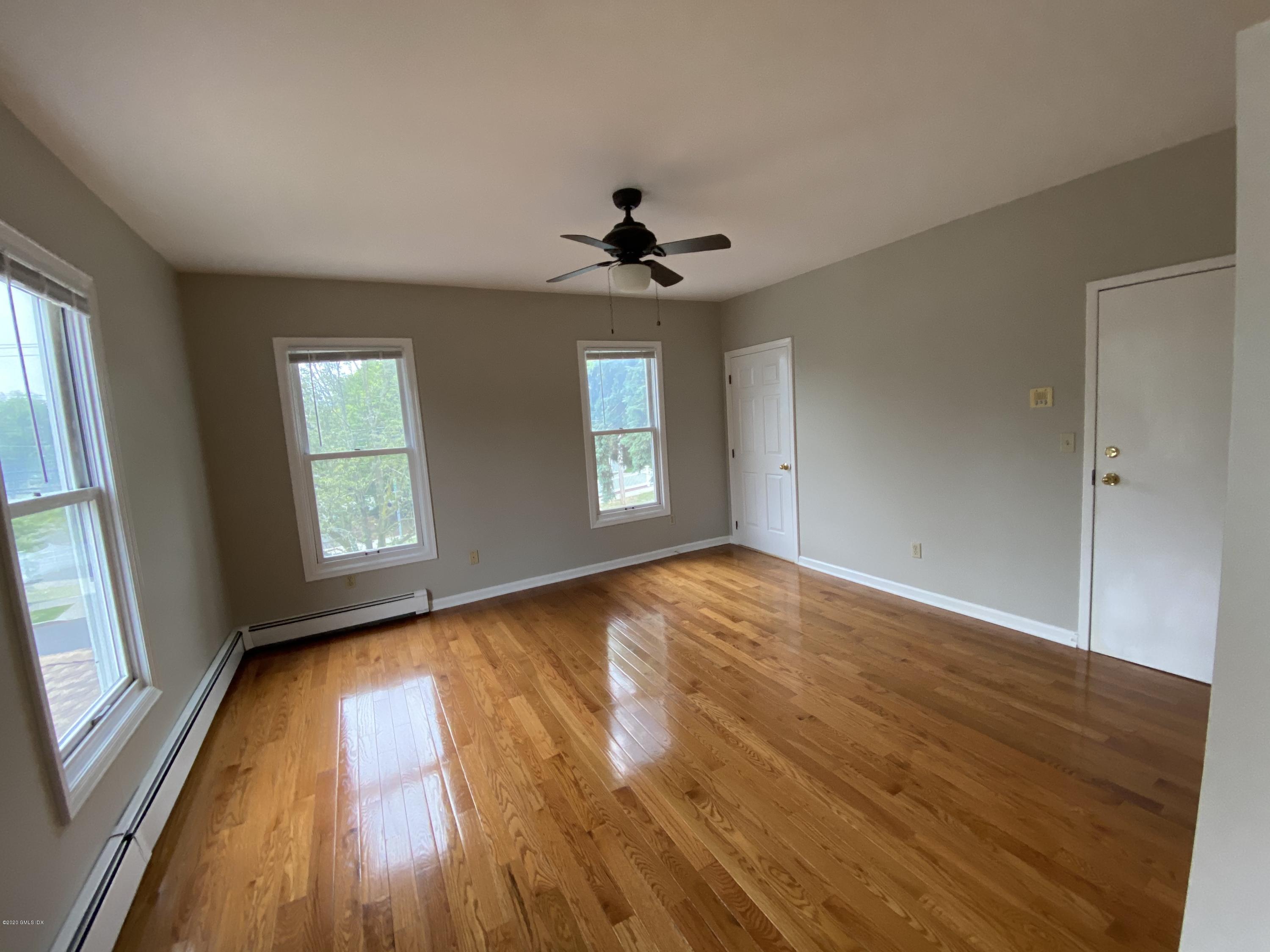 131 Mason Street, Unit 2 Greenwich, CT 06830 - Photo 3 of 14 an empty room with wooden floor chandelier fan and windows
