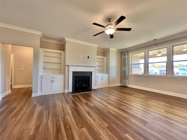 a view of an empty room with wooden floor fireplace and a window