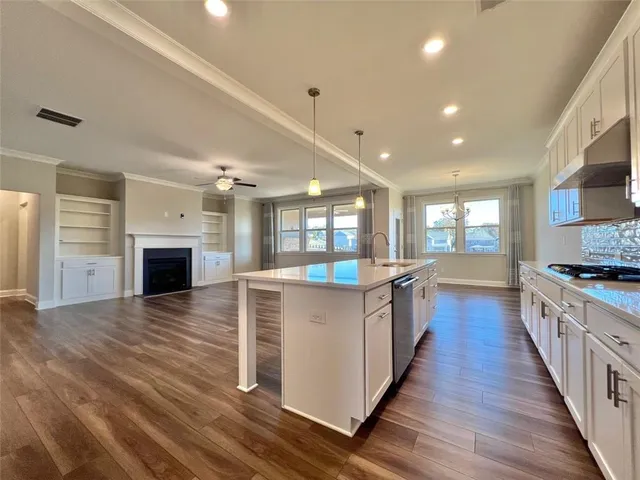 a large kitchen with kitchen island wooden floors granite counter tops and white stainless steel appliances