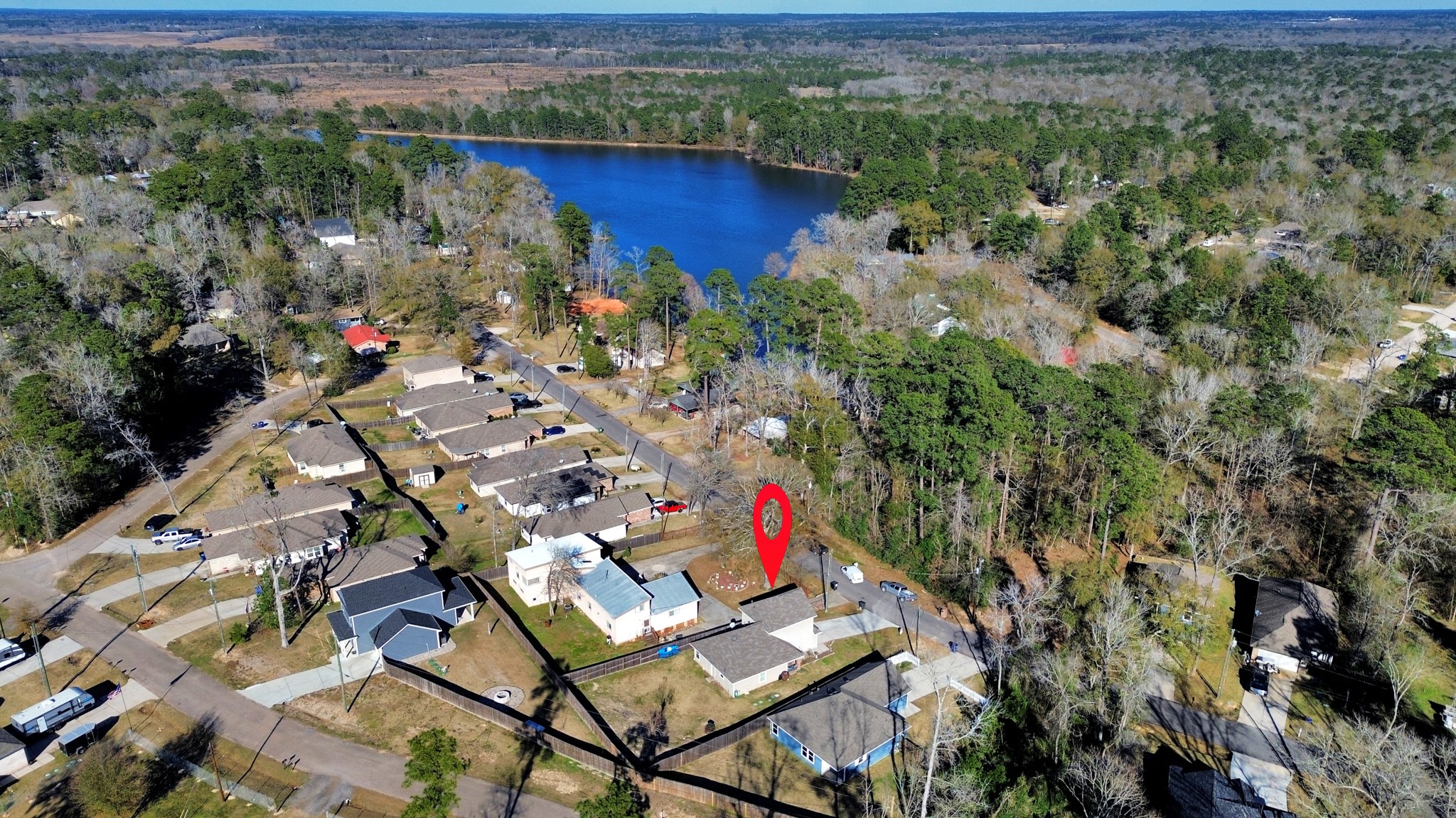 15291 Arrowhead Loop West Willis, TX 77378 - Photo 1 of 28 This aerial photo shows a charming neighborhood with a highlighted property near a serene lake. The area offers a peaceful and scenic environment. Ideal for buyers seeking a tranquil lakeside community.