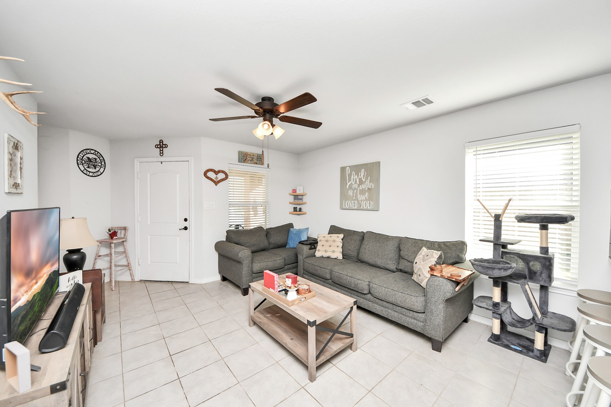 15291 Arrowhead Loop West Willis, TX 77378 - Photo 9 of 28 Bright, cozy living room with a modern ceiling fan, tile flooring, and ample natural light.