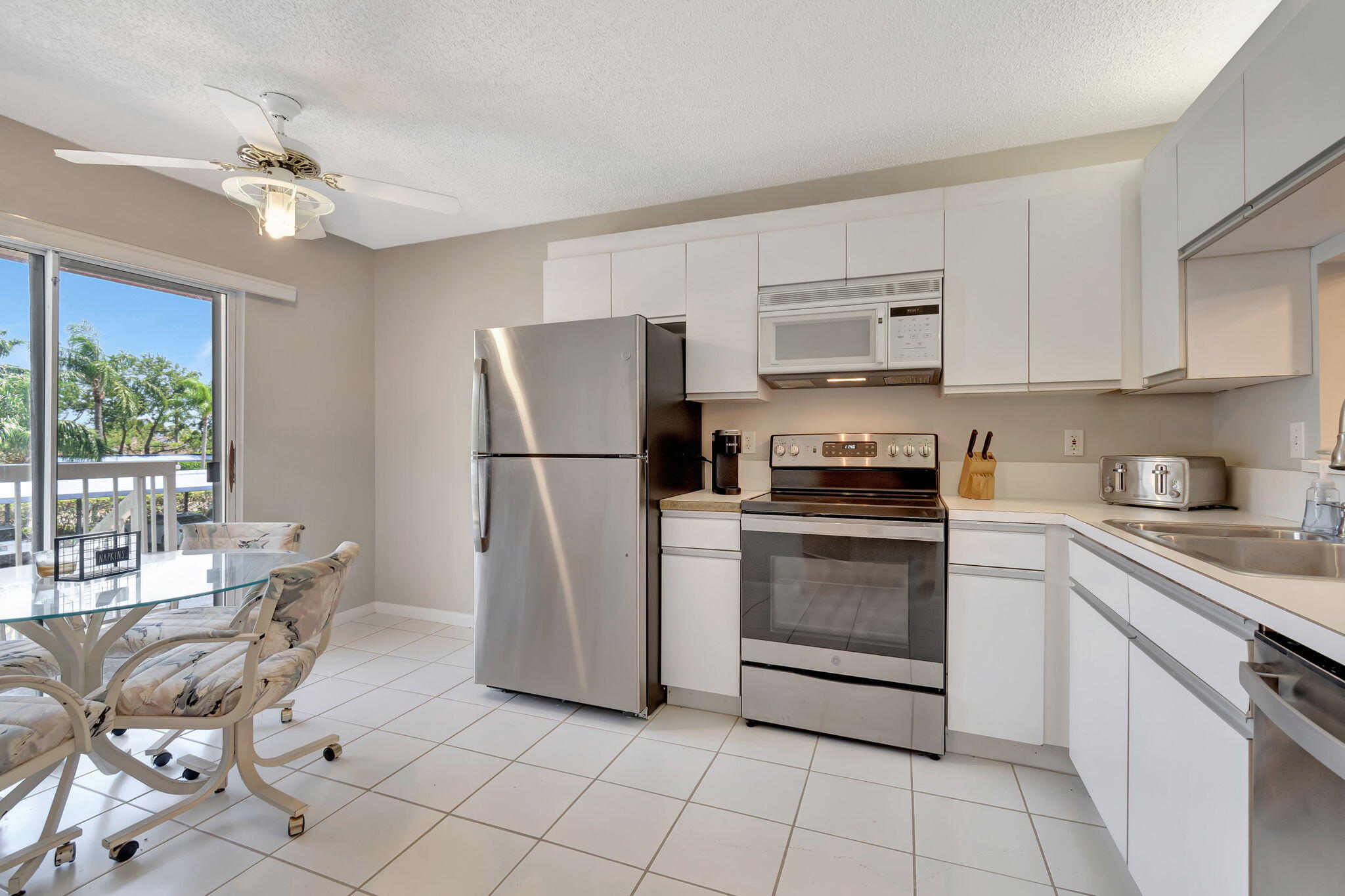 280 Northwest 67th Street, Unit B 207 Boca Raton, FL 33487 - Photo 5 of 13 a kitchen with a refrigerator a stove a sink and white cabinets