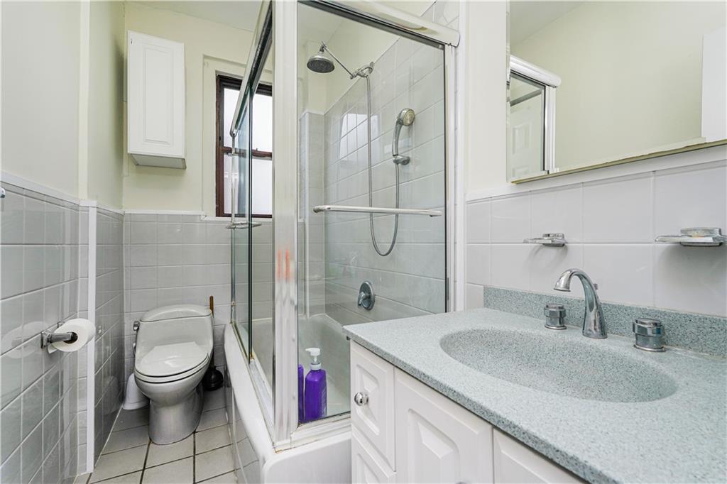 351 Marine Avenue, Unit F11 Brooklyn, NY 11209 - Photo 14 of 23 a bathroom with a granite countertop sink a toilet and shower