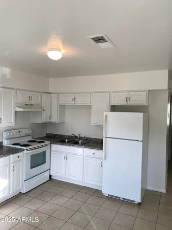 a kitchen with granite countertop white cabinets and white appliances