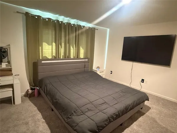 a bedroom with a bed and a flat tv screen on dresser