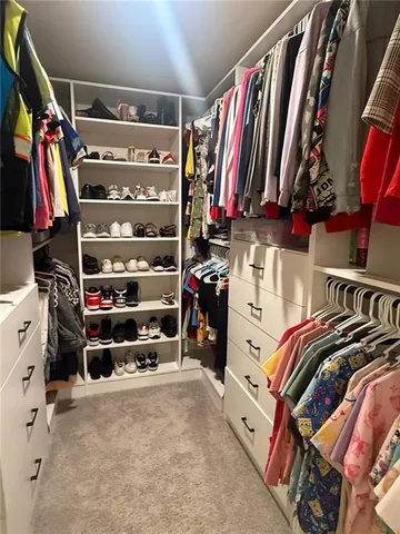 a view of walk in closet with clothes and shoes